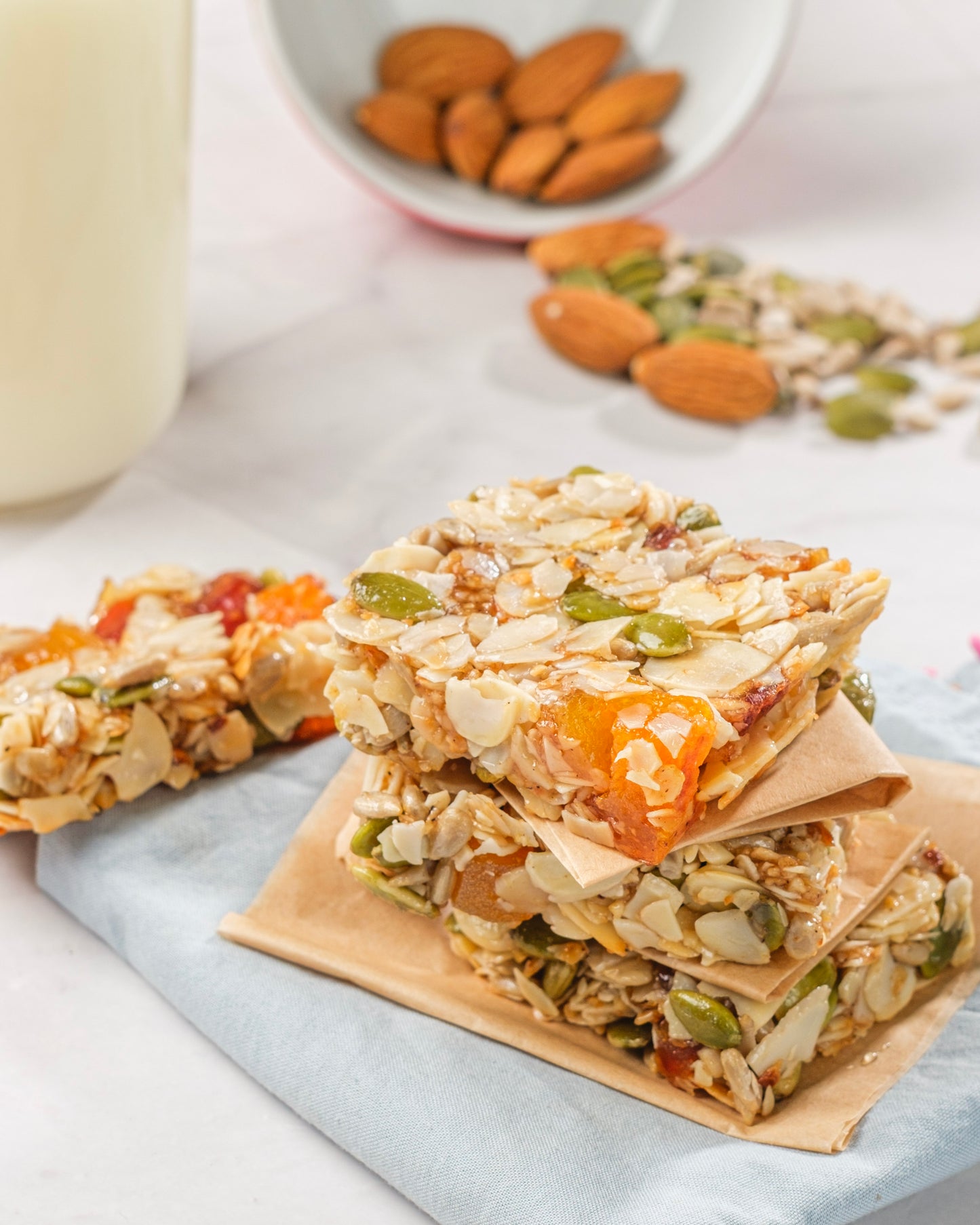 Stack of granola bars with almonds and seeds on a light surface